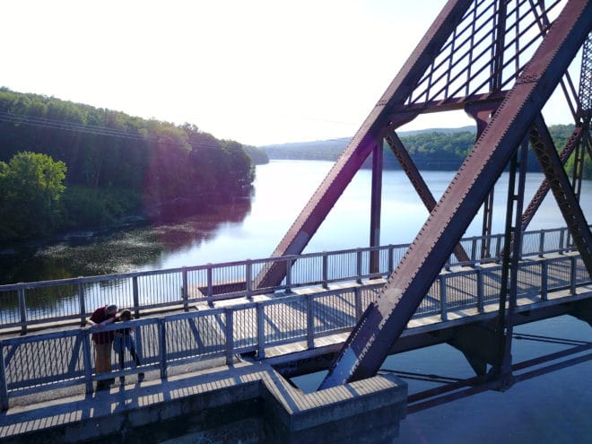 Steel railroad bridge over scenic blue Croton Dam, along the North County Trailway in Westchester County, New York.